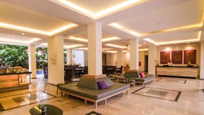 A spacious lobby with a reception desk, seating areas, and a bar.