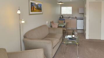 A living room with a sofa, a glass coffee table, and a floor lamp.