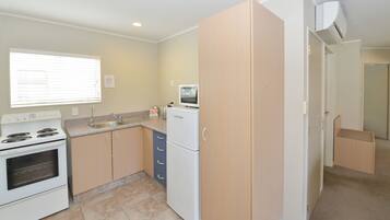 A compact kitchen with a stove, sink, microwave, and cabinets.