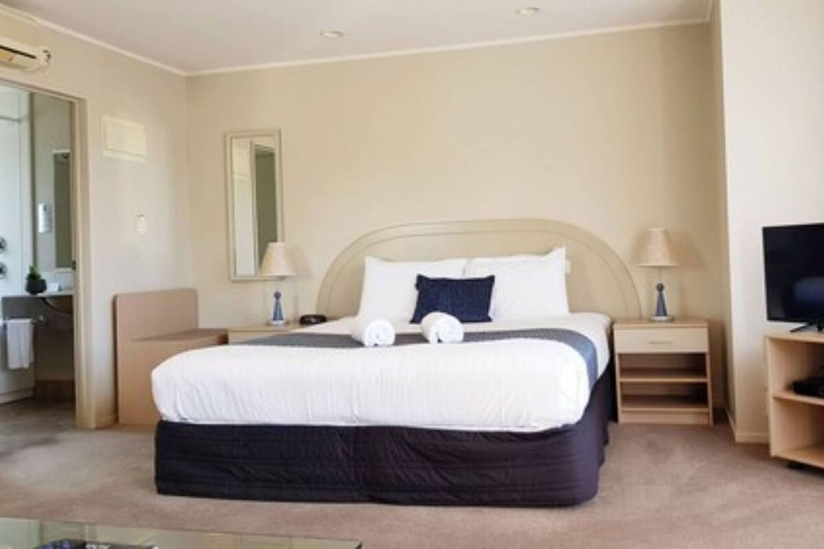 Een hotelkamer met een bed, nachtkastjes, een televisie en een spiegel.