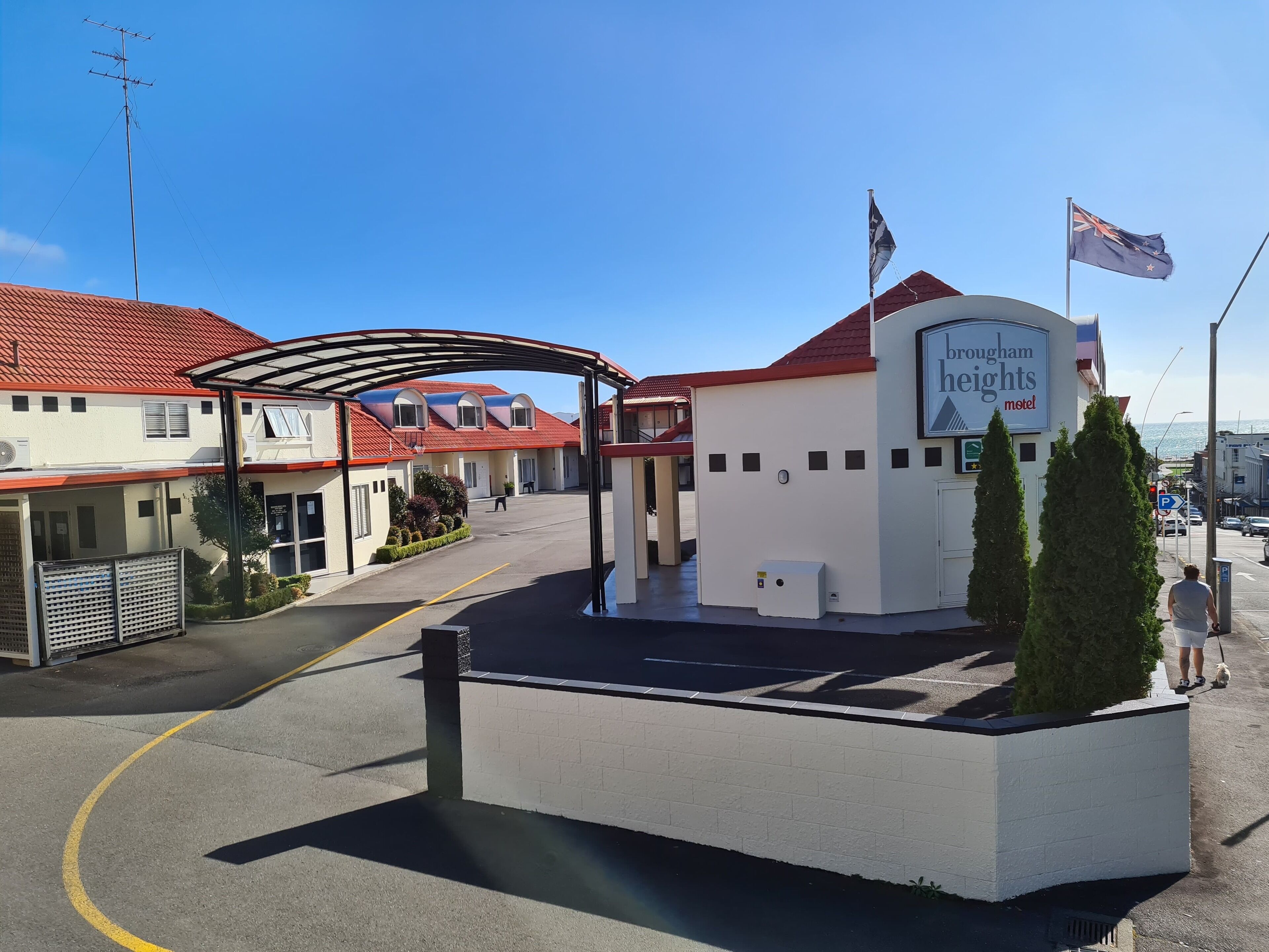 Un motel con techo rojo, entrada cubierta y un letrero que dice 'Hougham Heights Motel'.