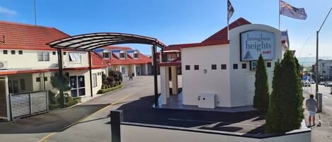 Un motel con techo rojo, entrada cubierta y un letrero que dice 'Hougham Heights Motel'.