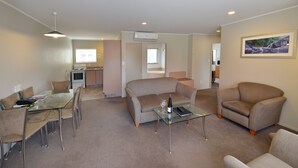 Una sala de estar moderna con una mesa de centro de vidrio, sofás color beige y un comedor con sillas.