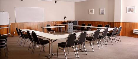 A conference room with a long table, chairs, a whiteboard, and a projector.