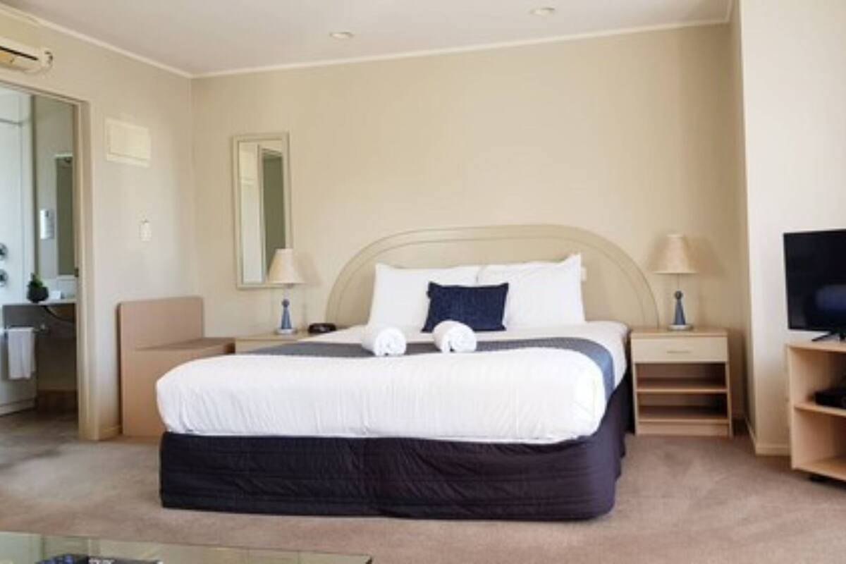 Een hotelkamer met een groot bed, twee nachtkastjes, een televisie en een spiegel.