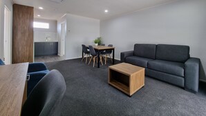 Una sala de estar moderna con un sofá gris, una mesa de centro de madera y un comedor con una mesa y sillas.