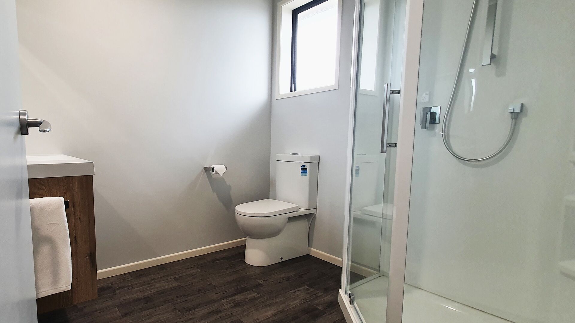 A small, modern bathroom with a toilet, sink, and glass shower enclosure.