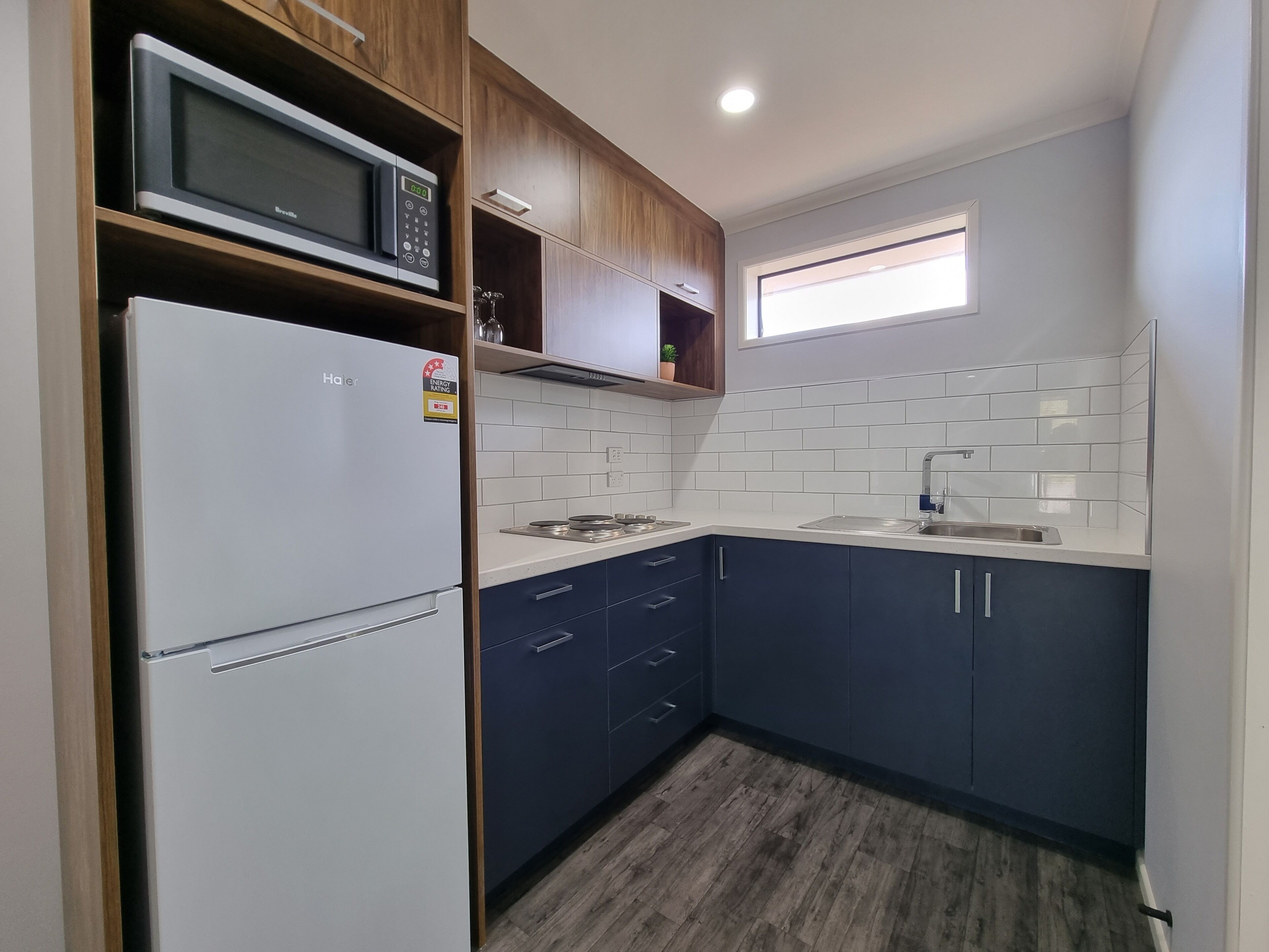 A compact kitchen with a white refrigerator, a microwave, and a sink.