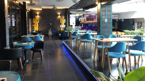 Ein Restaurant mit blauen Stühlen, Tischen und einer Bühne für Live-Musik.