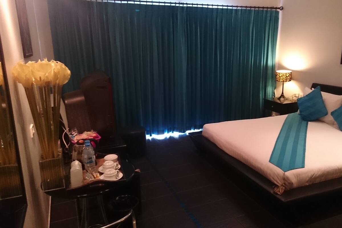 Una habitación de hotel con cama, escritorio, silla, lámpara y un cuadro en la pared.