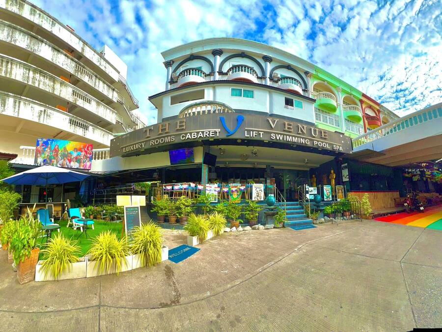 Un hotel con facciata curvilinea, numerosi balconi e insegna che indica camere di lusso, ascensore, piscina e centro benessere.