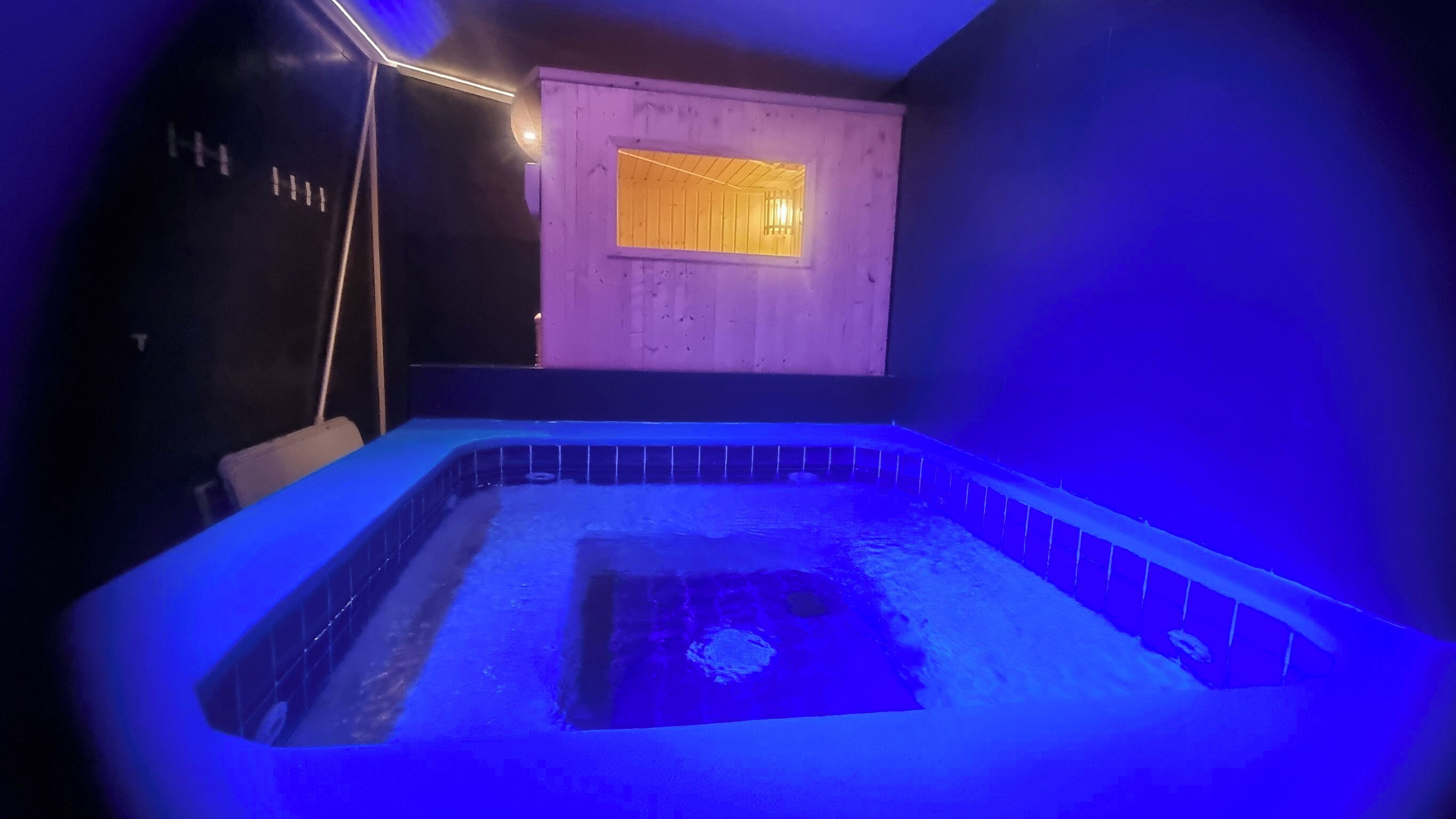 A spa room with a hot tub, wooden walls, and a window.