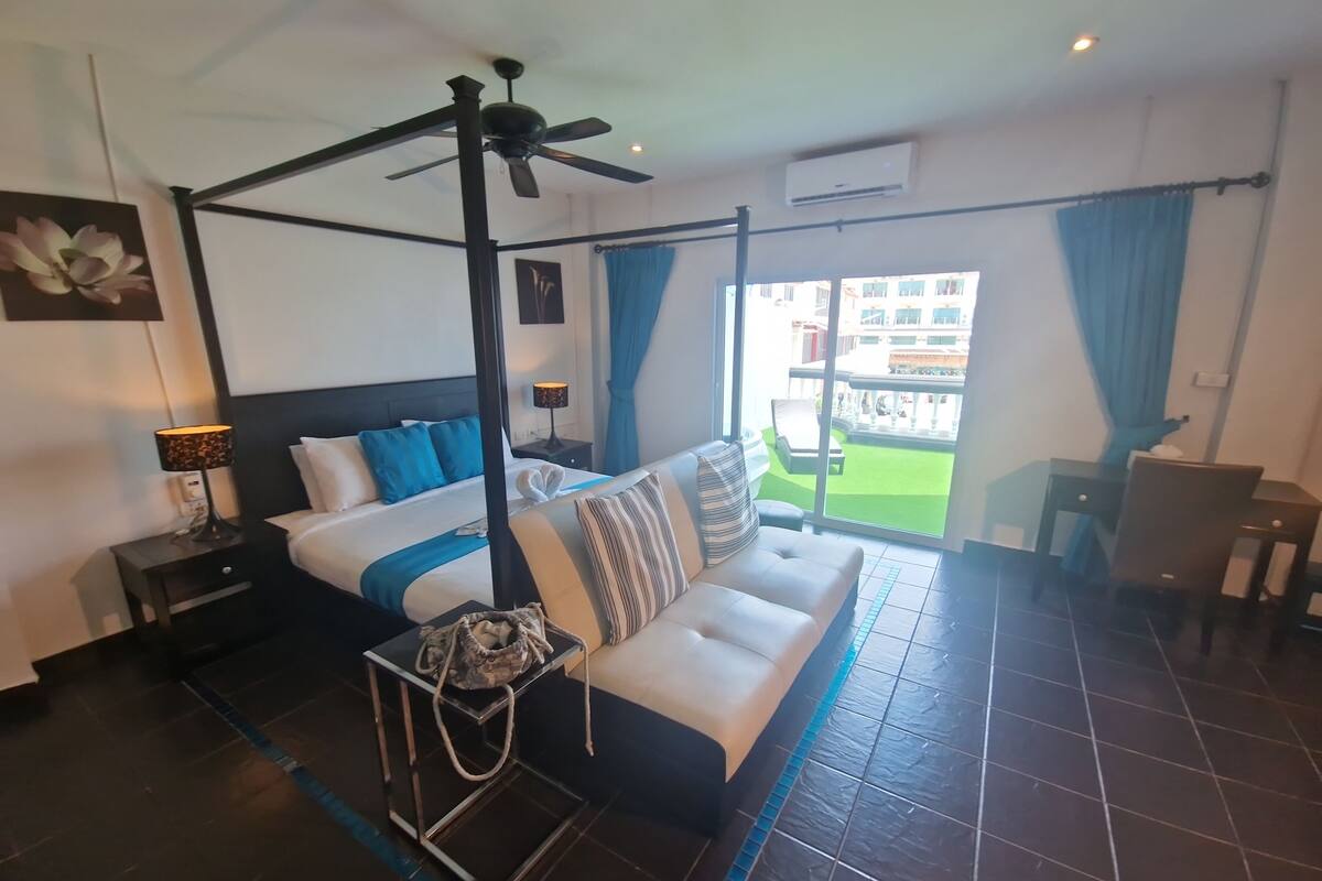 Una habitación de hotel moderna con una cama con dosel, un sofá, una mesita y un ventilador de techo.