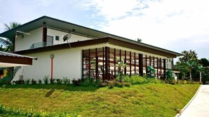 Une maison à deux étages avec un porche couvert, une antenne parabolique et un petit jardin.