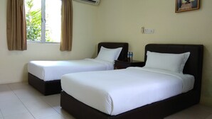 Une chambre d’hôtel avec deux lits, une fenêtre avec des rideaux, un appareil de climatisation, une table de chevet avec des bouteilles d’eau et un tableau encadré au mur.