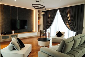 A modern living room with a flat-screen TV, a sofa, a coffee table, and a dining table. - La Villa Langkawi - Private Pool (Langkawi)