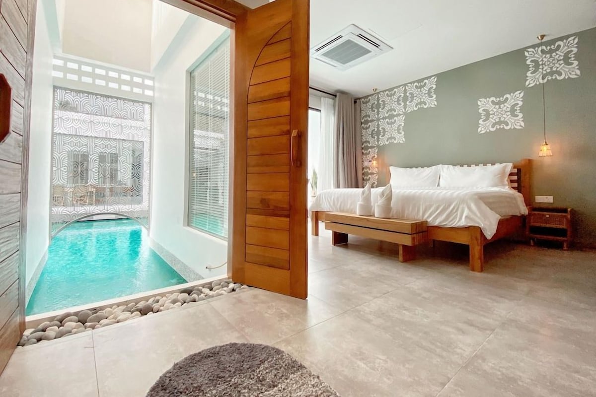 A bedroom with a bed, bedside tables, and a view of a swimming pool.
