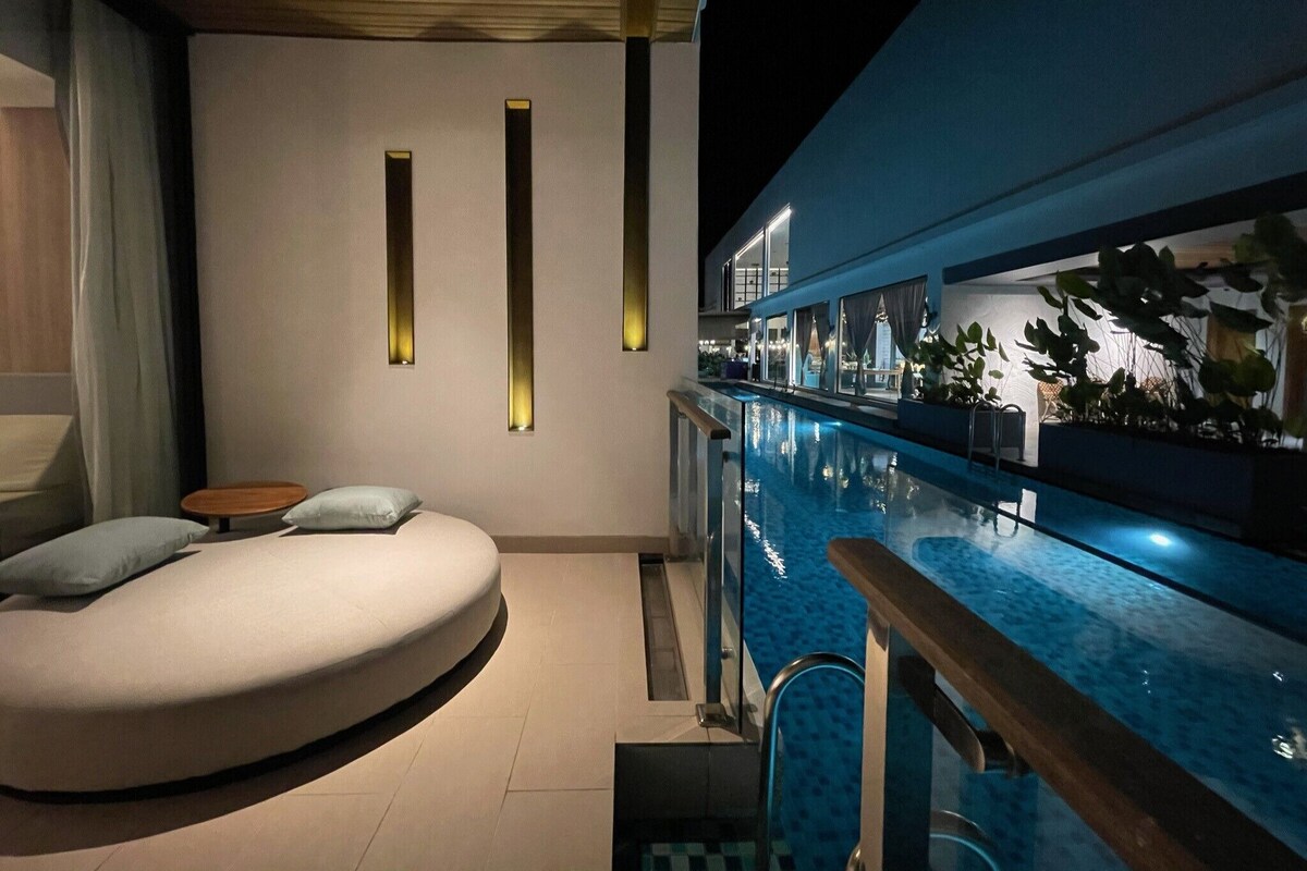A modern indoor pool area with a curved seating area and a view of the pool.