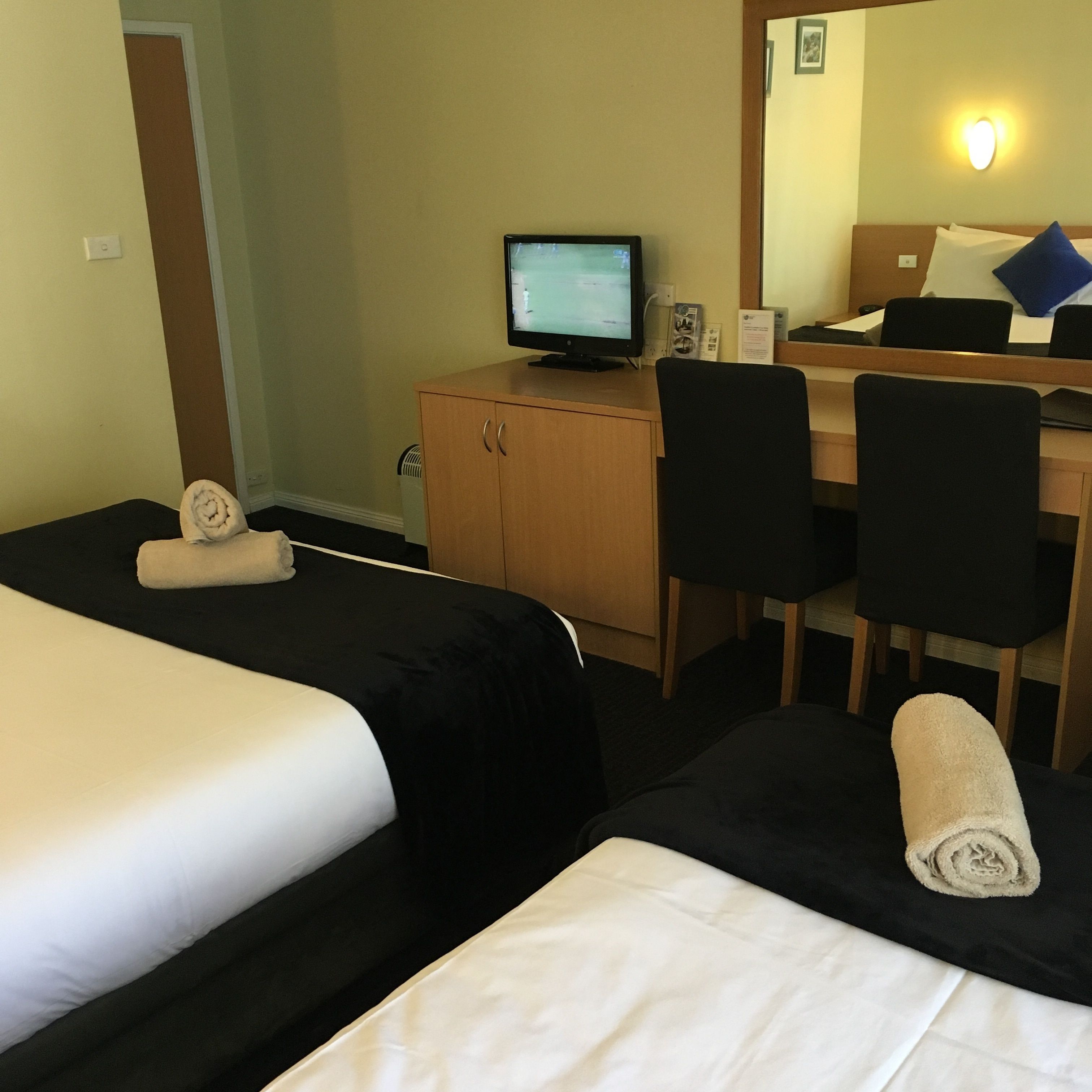 Een hotelkamer met twee bedden, een bureau, een computer en een spiegel.