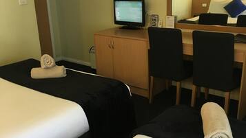 Een hotelkamer met twee bedden, een bureau, een computer en een spiegel.