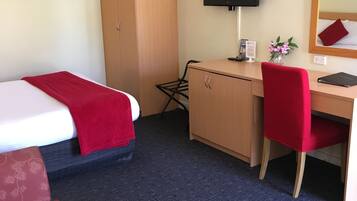 Ein Hotelzimmer mit Bett, Schreibtisch, Stuhl, Fernseher und Kleiderschrank.