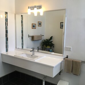 A modern bathroom with a large white sink, a mirror, and a towel rack. - Sky Rider Motor Inn (Katoomba)