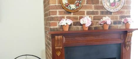 Una chimenea de ladrillo con placas decorativas en la parte superior y plantas en macetas sobre la repisa.