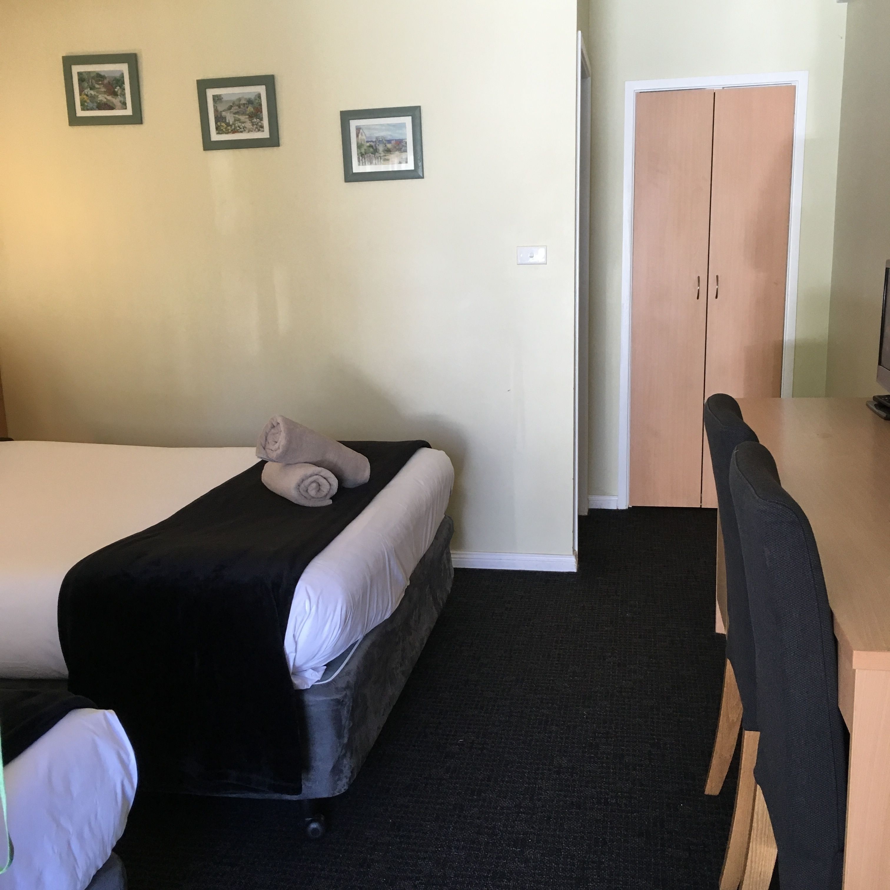 Una habitación de hotel con dos camas, un escritorio y un armario.