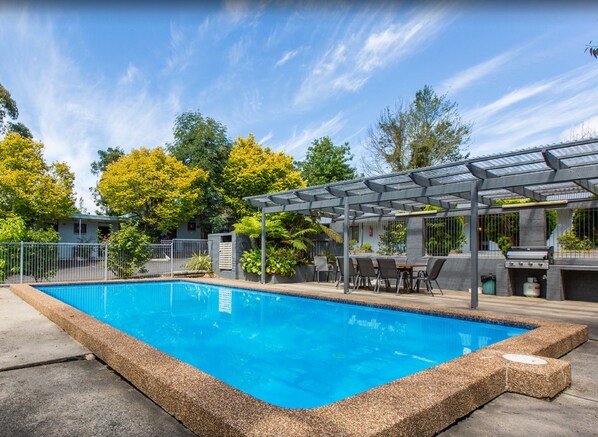 Una piscina al aire libre, sillones reclinables de piscina