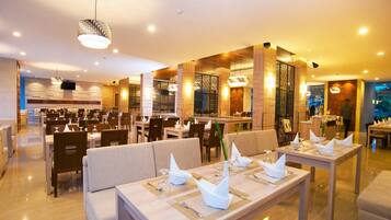 A spacious restaurant with multiple dining areas, each with neatly set tables and chairs.
