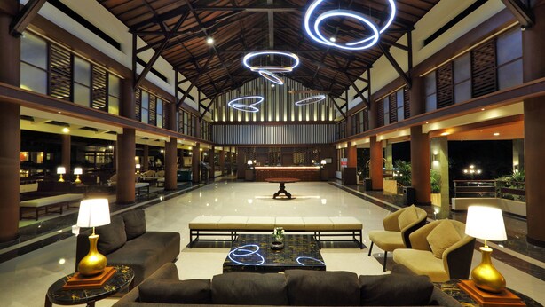 Um hall amplo com teto alto, luminárias modernas e áreas de estar confortáveis.
