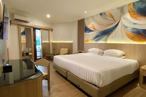 A hotel room with a large bed, a desk, a chair, and a TV.