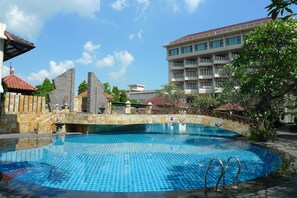 A swimming pool with a tiled pattern, surrounded by a stone wall and a wooden fence.