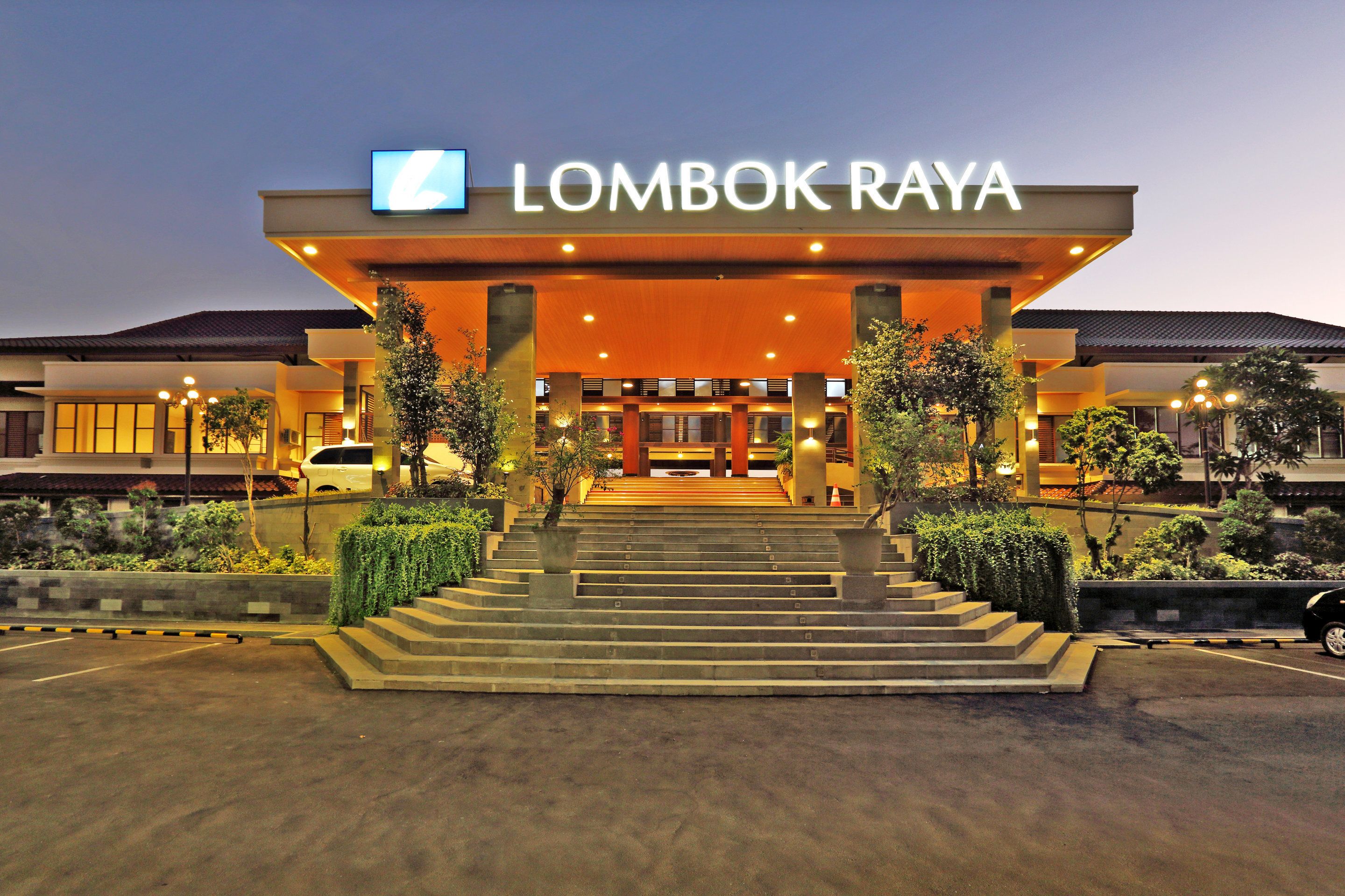A hotel entrance with a sign reading "LOMBOK RAYA" and a staircase leading up to the entrance.