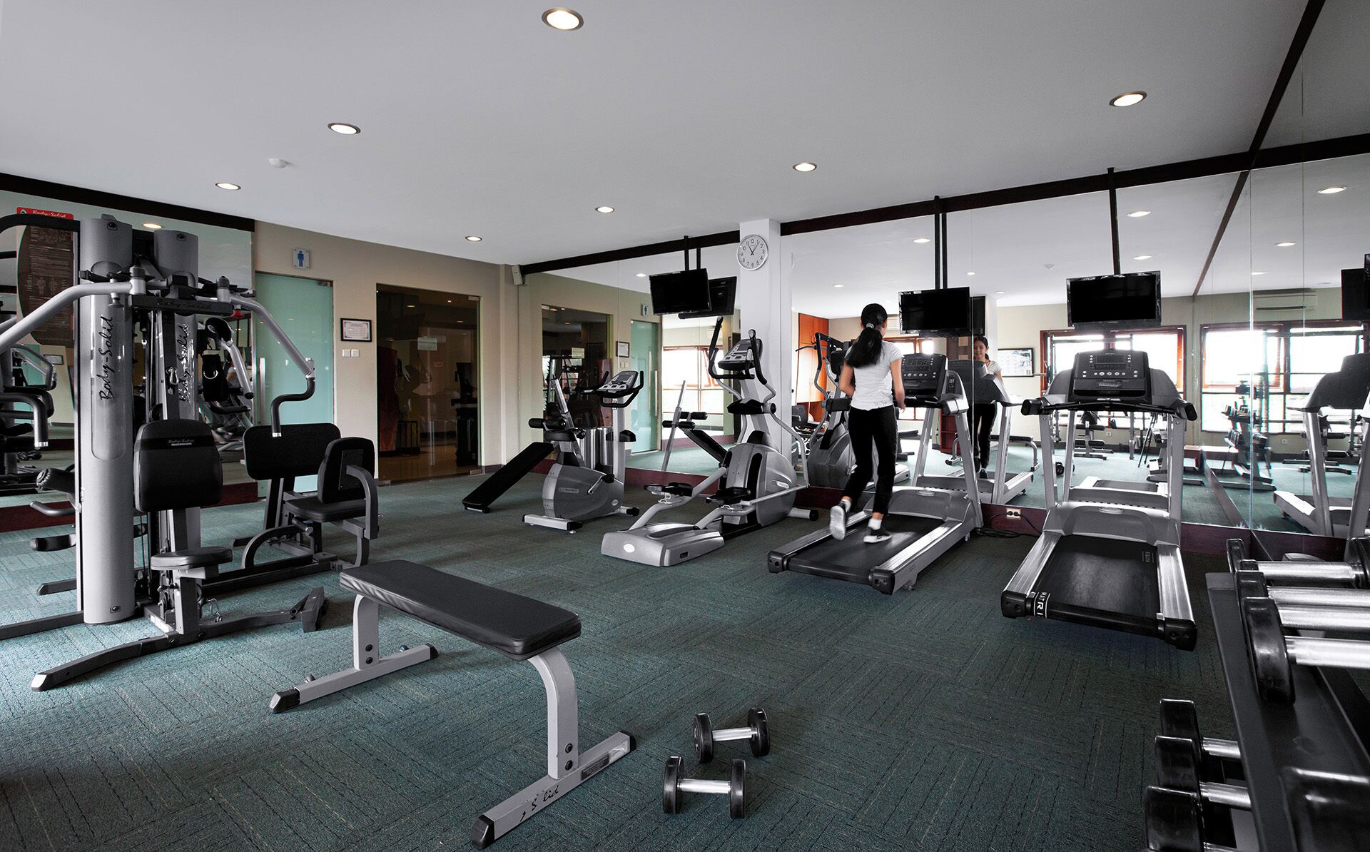 A gym with treadmills, weight machines, and a bench.