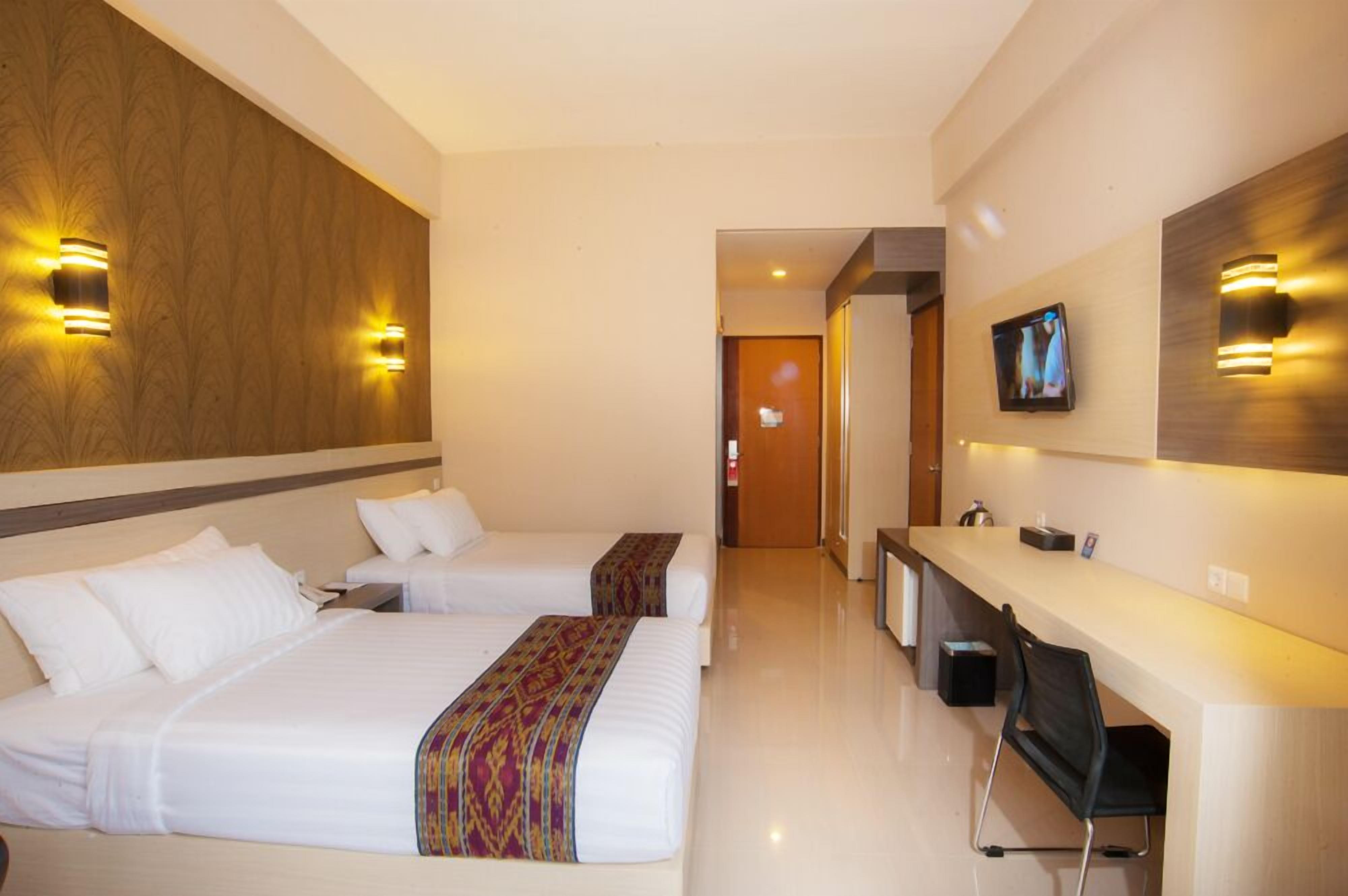 A hotel room with two beds, a desk, and a television.