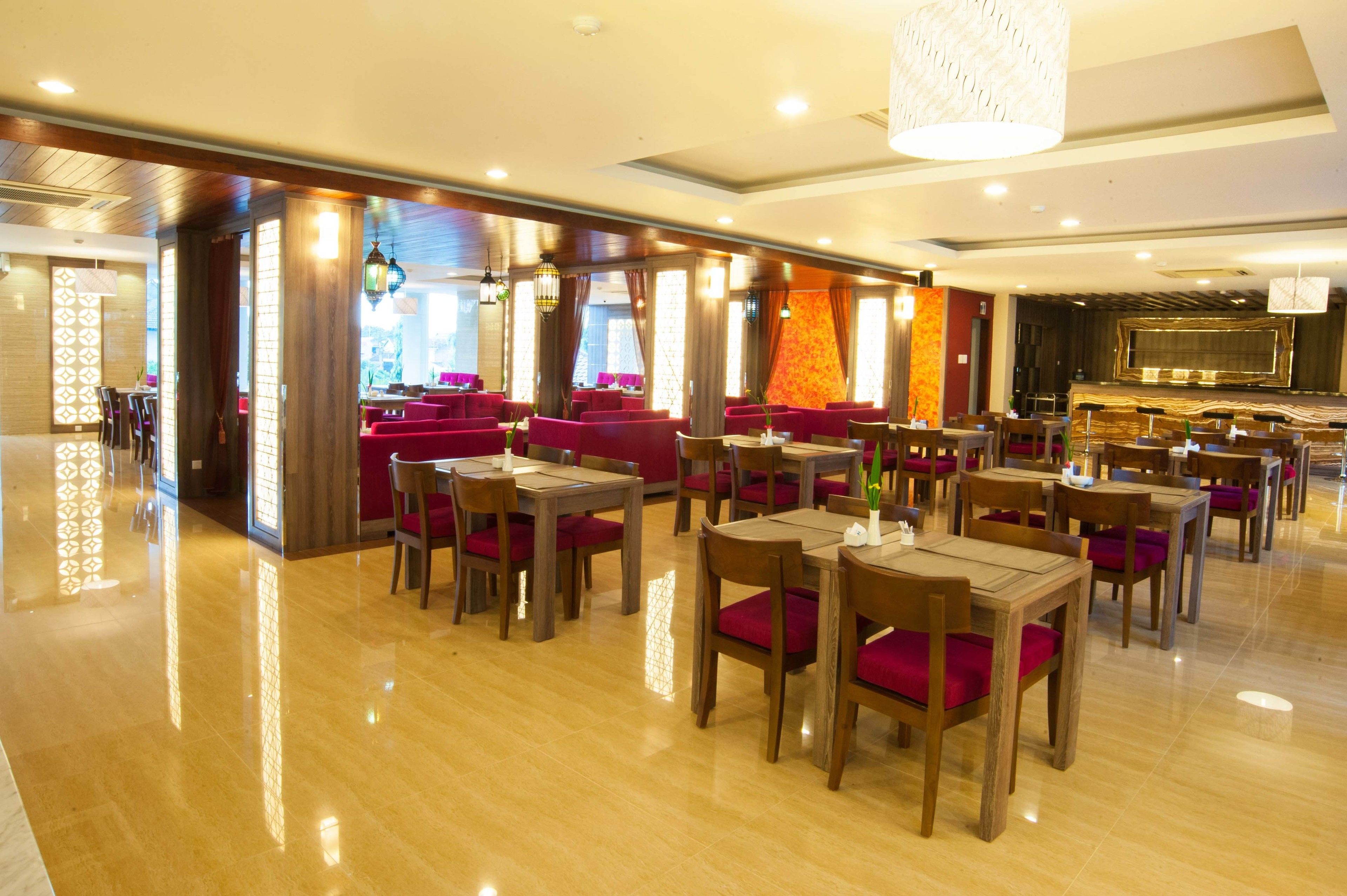 Ein Restaurant mit Holztischen und roten Sitzgelegenheiten, einer Bar und einem großen Bildschirm.