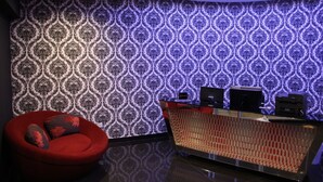 Uma área de recepção com papel de parede estampado, um sofá vermelho e um balcão de atendimento.
