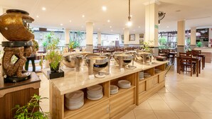 Un área de bufé con varias estaciones de servicio, muebles de madera y plantas en macetas.