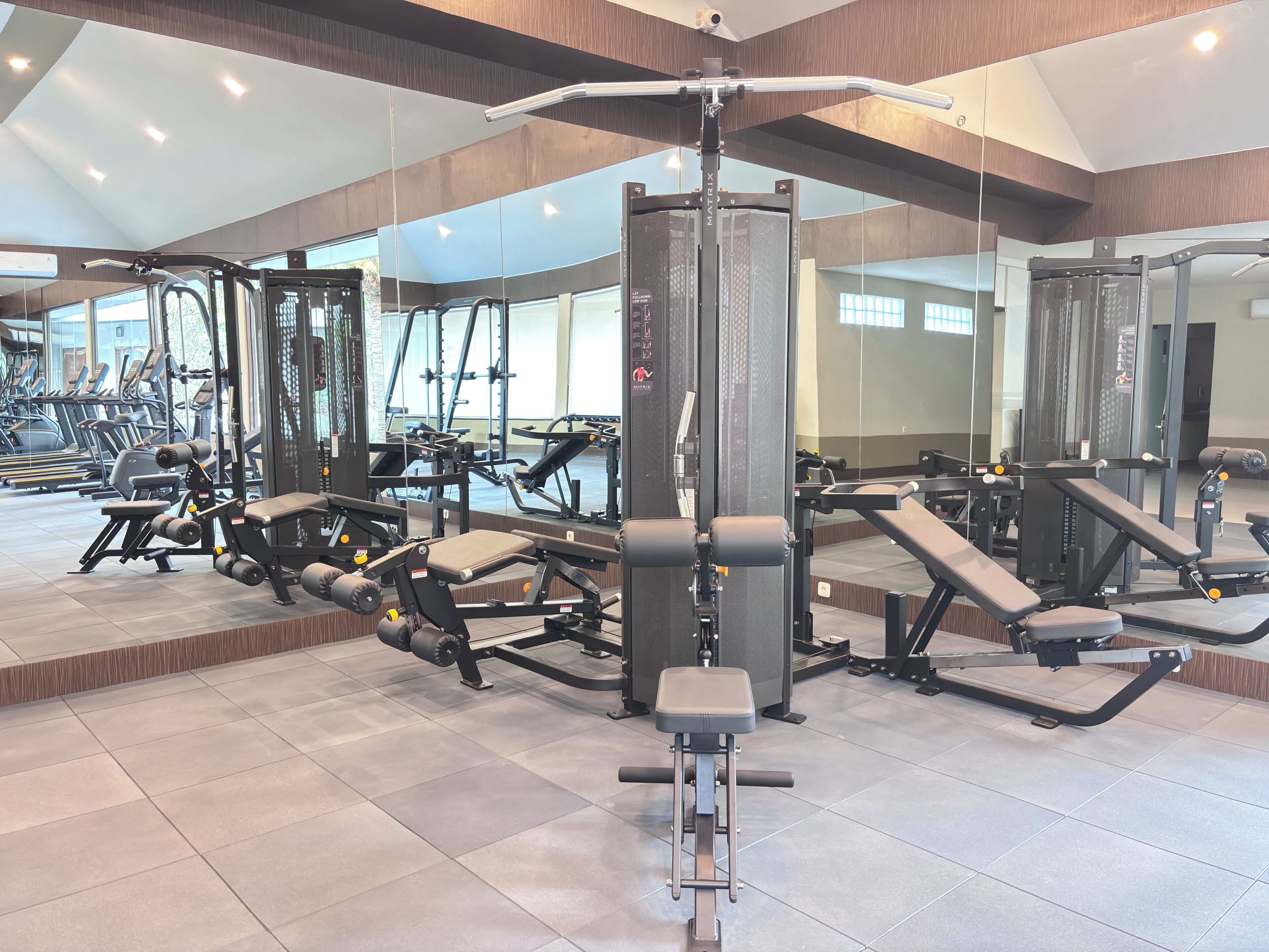 Een sportschool met diverse trainingsapparaten, grote ramen en een modern design.