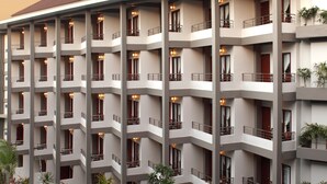 Un hotel con varios balcones, piscina y zonas de estar al aire libre.