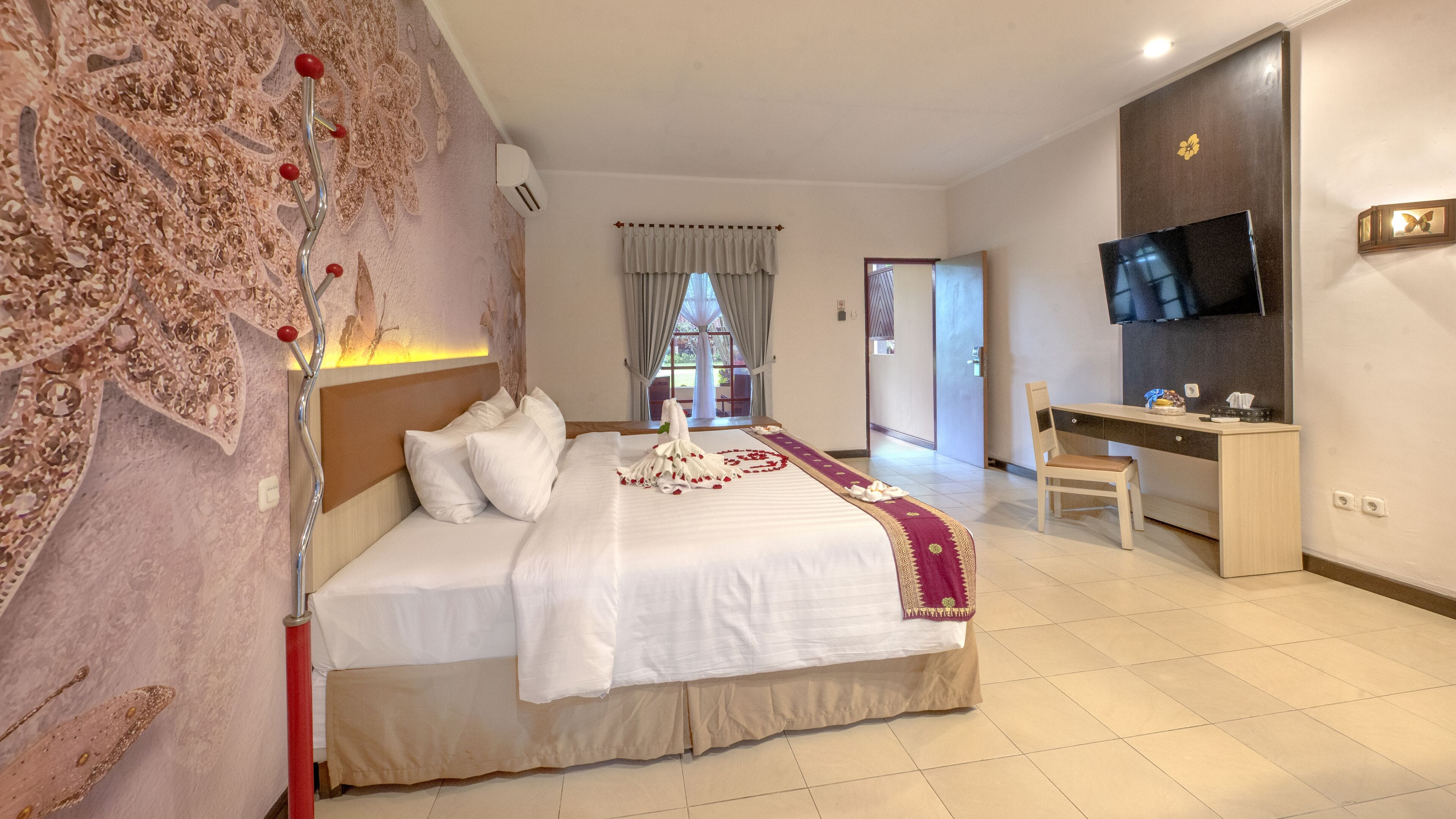 A hotel room with a large bed, a desk, a TV, and a view of the outdoors.