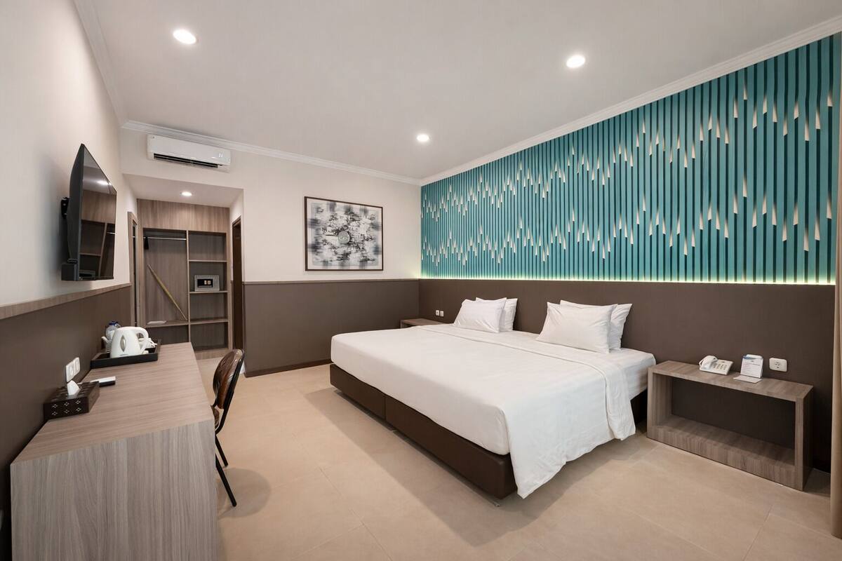 A modern hotel room with a large bed, a desk, a wardrobe, and a wall-mounted TV.