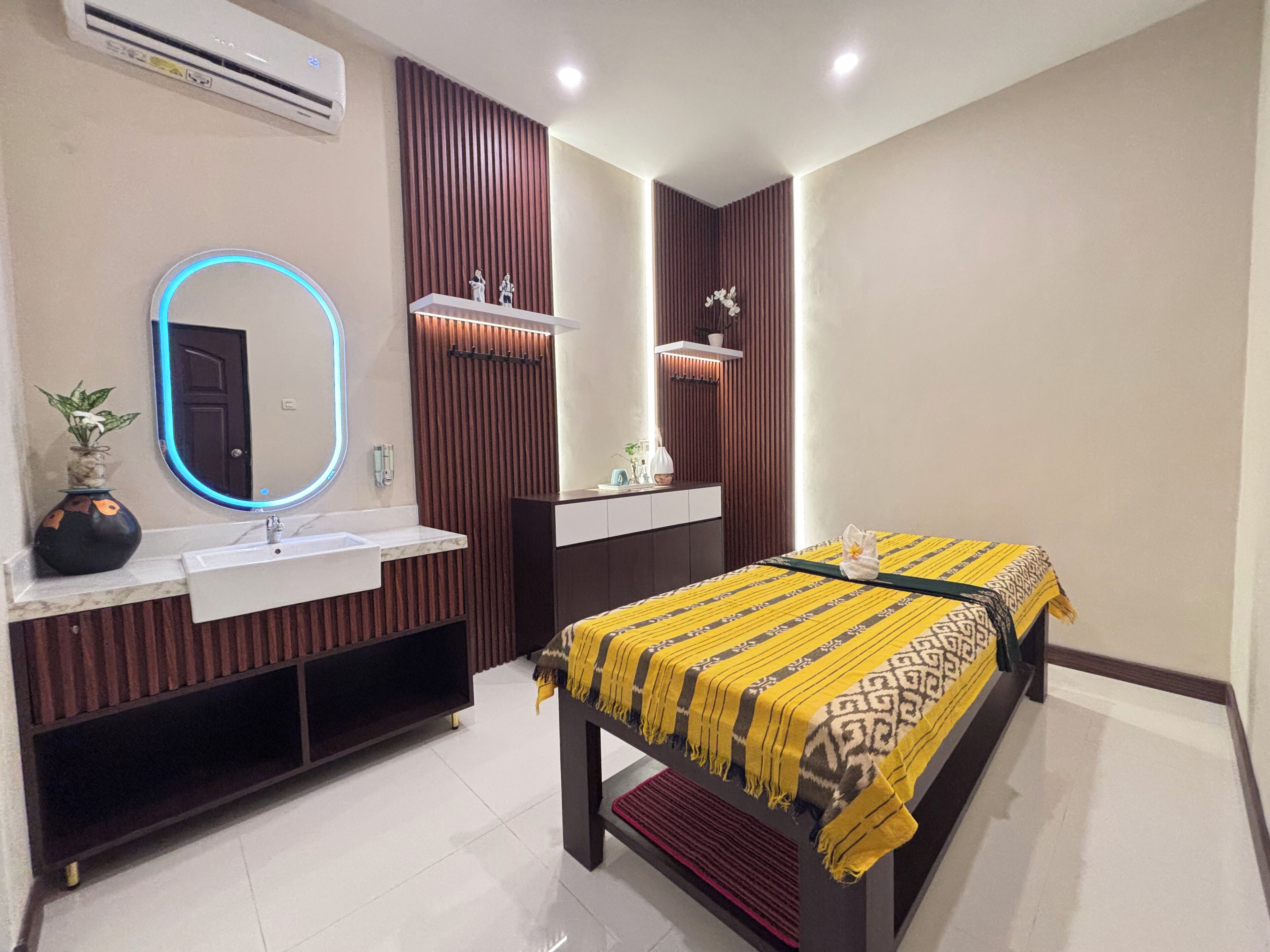 A modern bedroom with a bed, a vanity with a mirror, and a wall-mounted air conditioner.