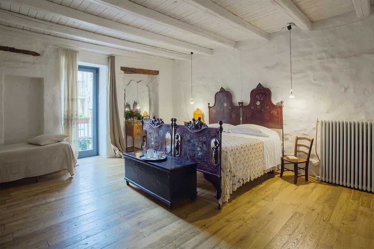 A bedroom with a wooden bed, a dresser, a chair, and a radiator.