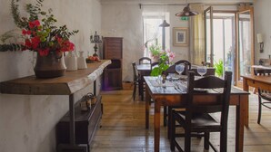 A rustic dining area with wooden furniture, a long table, and a bench. There are potted plants and candles on the table. - Wundergarten Dimora dei Frati (Gratteri)