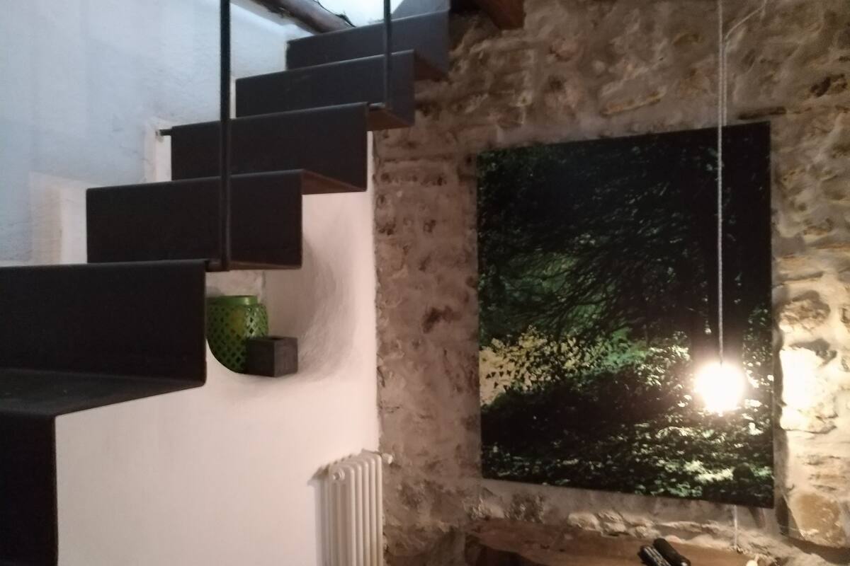 A staircase with a stone wall and a large window displaying a night scene.