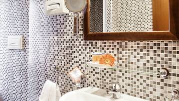 Un baño con lavamanos blanco, un bidé y un espejo.