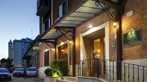 L’entrée d’un hôtel, avec un porche abrité, des marches menant à la porte et une enseigne indiquant le nom de l’hôtel.