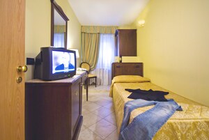 Una camera d'albergo con un letto, una televisione, una scrivania e un armadio.